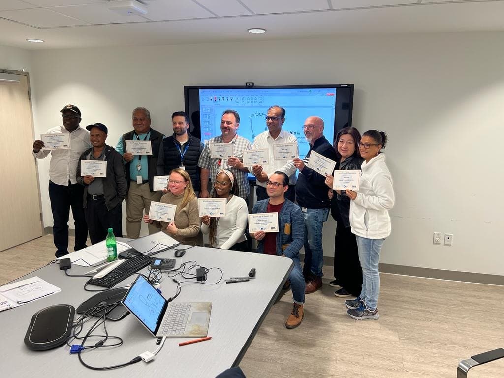 Thirteen participants holding up their certificates of completion at the end of a corporate training course.