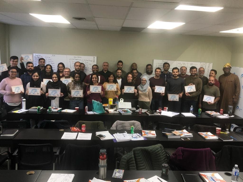 About thirty participants holding their certificates at the end of a classroom training session.