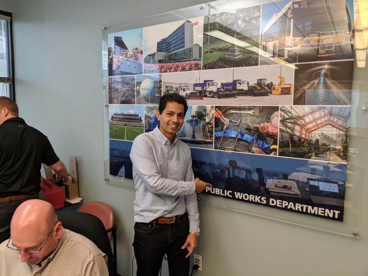 Hemant Dhariyal beside the City of Hamilton Public Works Department board during a session, with a participant working at the table behind him.