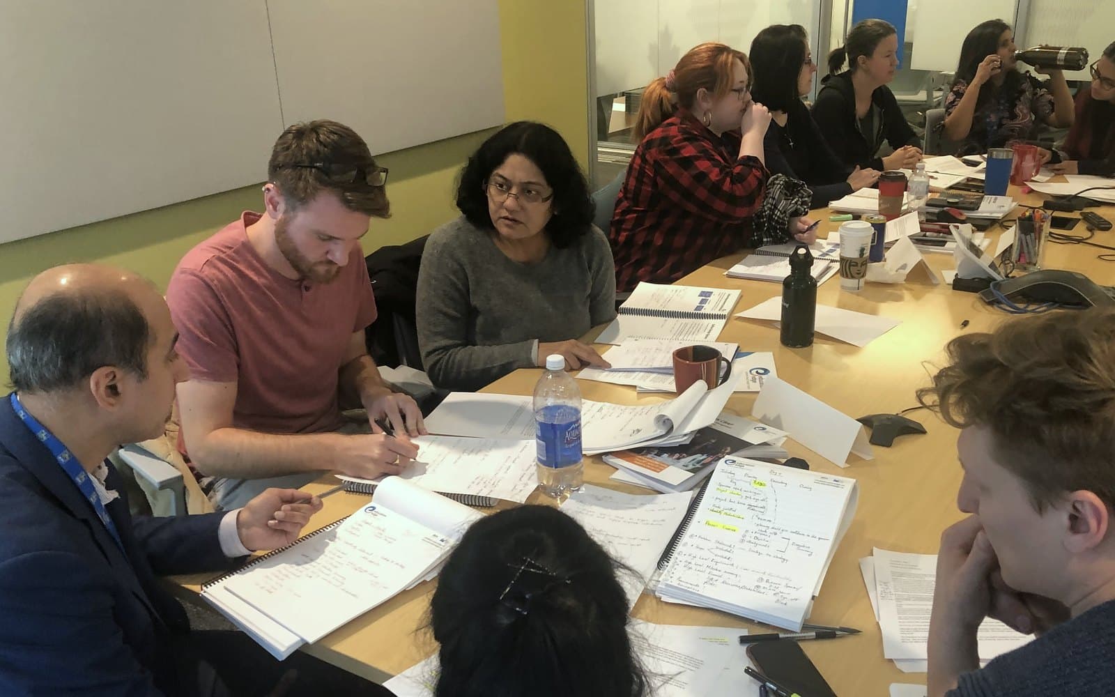 Participants working through Education Edge business analysis workbooks around a boardroom table.