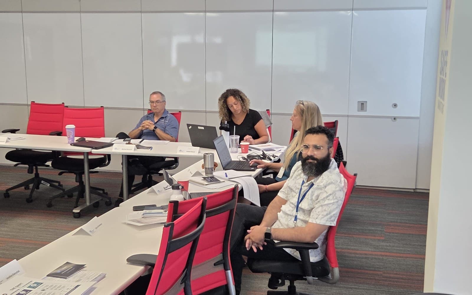 A small group working at a boardroom table with laptops open during a training session.
