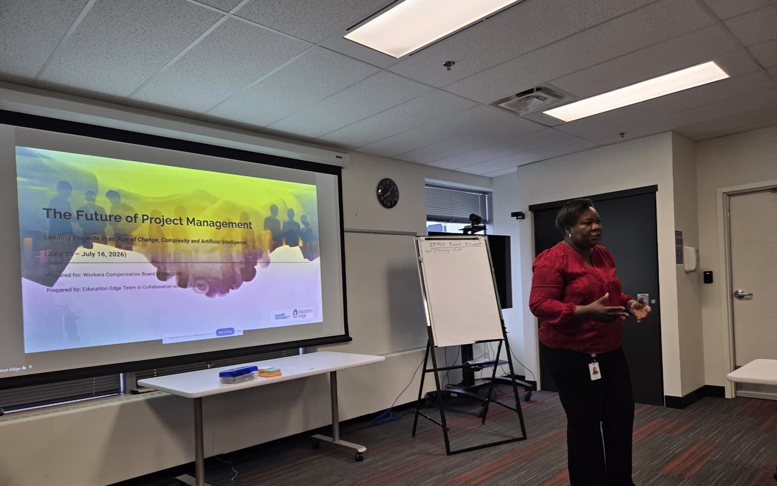 A presenter mid-sentence beside a projected title slide reading The Future of Project Management, prepared for the Workers Compensation Board of Manitoba, July 2026.