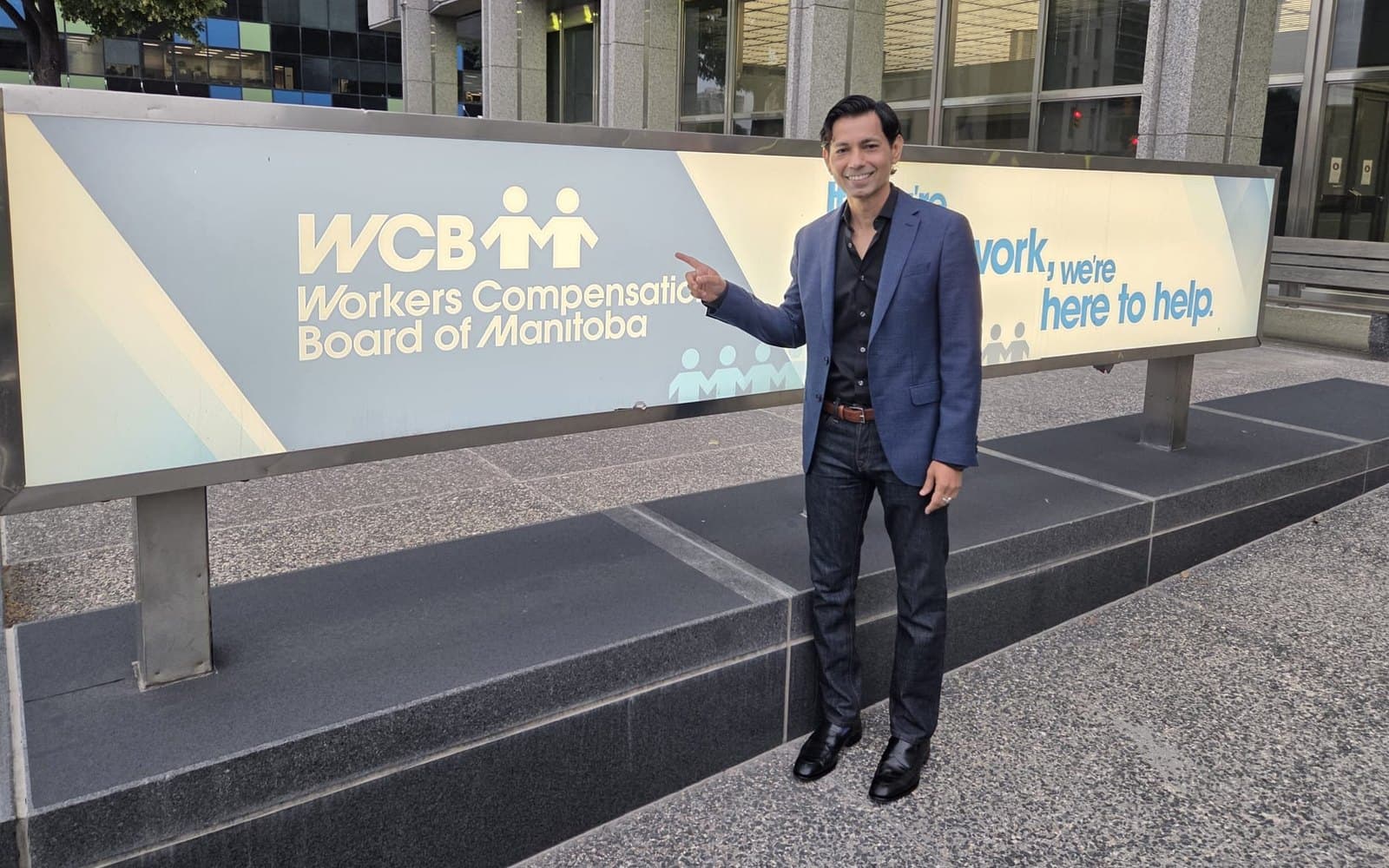Hemant Dhariyal standing beside the Workers Compensation Board of Manitoba monument sign outside the board's Winnipeg office.